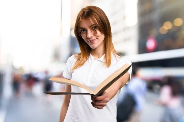 Bela jovem leitura livro sobre fundo desfocado — Fotografia de Stock