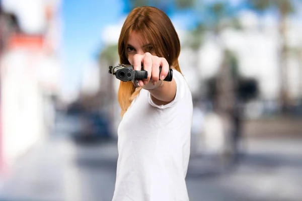 Szép, fiatal lány, egy pisztolyt tartó céltalan háttér — Stock Fotó