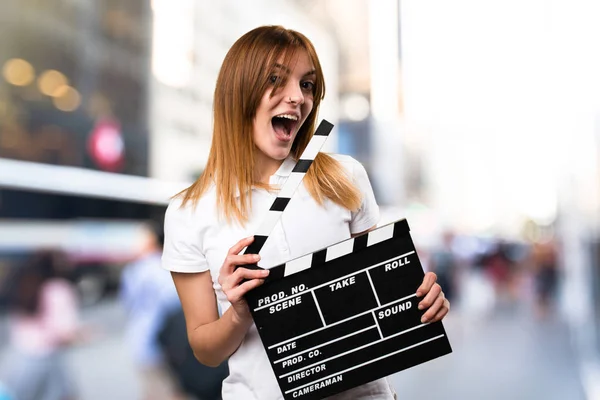 Verbaasd gelukkig mooi jong meisje een Filmklapper bedrijf op u — Stockfoto