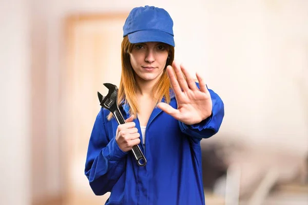 Delivery woman making stop sign on defocused background