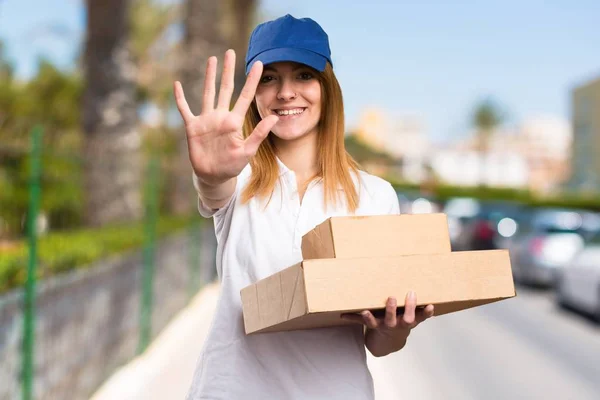 Delivery woman counting five on unfocused background
