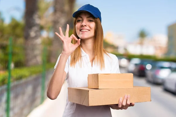 Delivery woman making OK sign on unfocused background