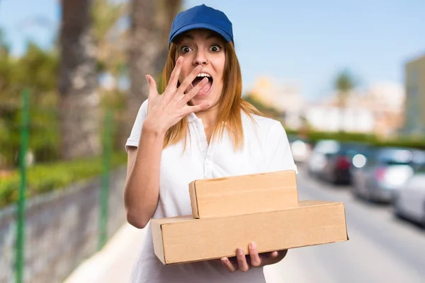Delivery woman making surprise gesture on unfocused background