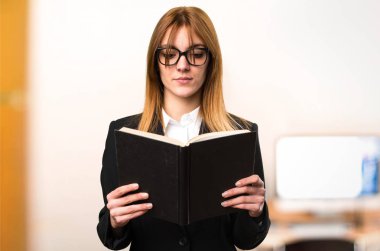 Ofiste genç iş kadını okuma kitabı odaklanmamış arka plan üzerinde