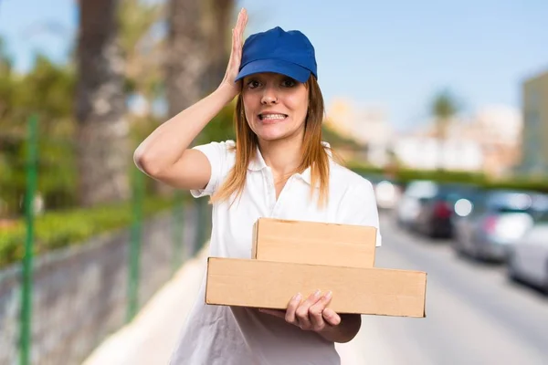 Delivery woman having doubts on unfocused background — Stock Photo, Image