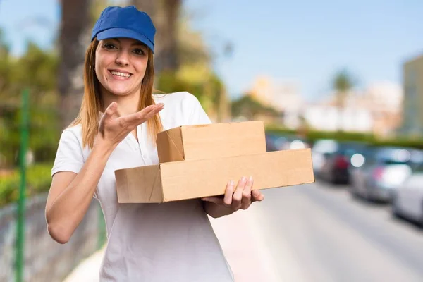 Delivery woman presenting something on unfocused background