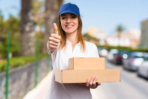 Delivery woman with thumb up on unfocused background