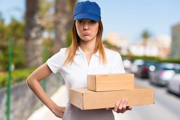 Sad delivery woman on unfocused background