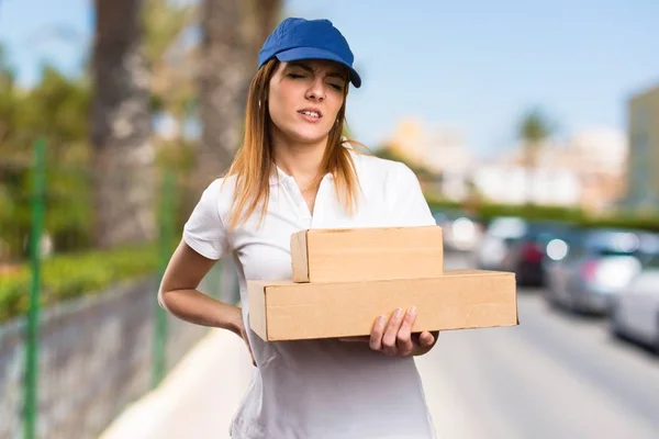 Delivery woman with back pain on unfocused background — Stock Photo, Image