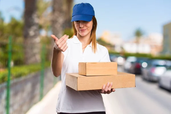 Delivery woman doing coming gesture on unfocused background