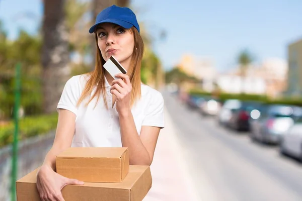 Delivery woman holding a credit card on unfocused background