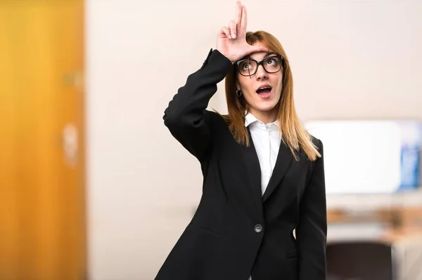 Unga företag kvinna gör förlorare tecken i office på ofokuserat bakgrund — Stockfoto