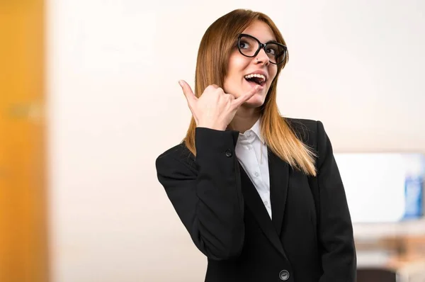 Jovem mulher de negócios fazendo gesto de telefone no escritório em fundo desfocado — Fotografia de Stock