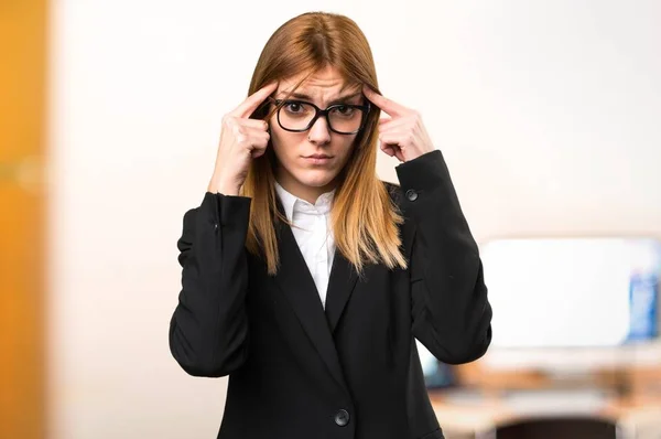 Giovane donna d'affari che pensa in ufficio su sfondo sfocato — Foto Stock