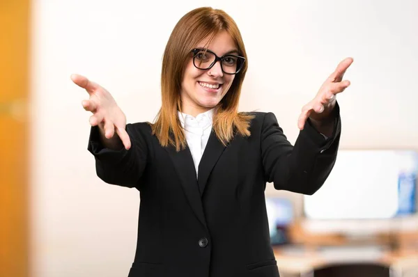Молодая деловая женщина представляет что-то в офисе на неориентированном фоне — стоковое фото