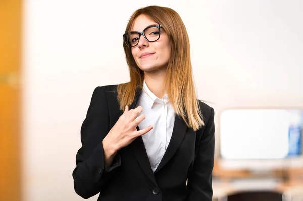 Joven mujer de negocios orgullosa de sí misma en la oficina en un fondo desenfocado —  Fotos de Stock