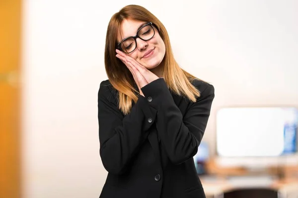 Young business woman making sleep gesture in the office on unfocused background