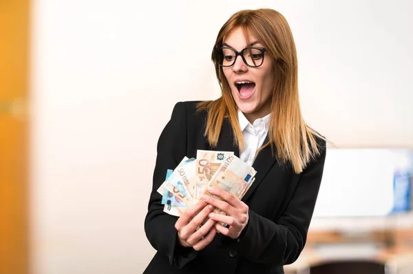 Fiatal üzleti nő vesz egy csomó pénzt a Hivatal a céltalan háttér — Stock Fotó
