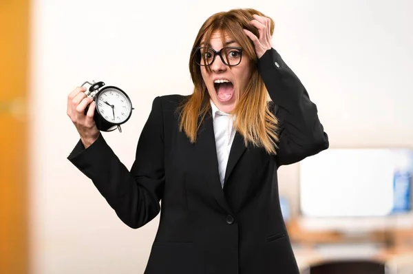 Ung affärskvinna holding vintage klocka i office på ofokuserat bakgrund — Stockfoto