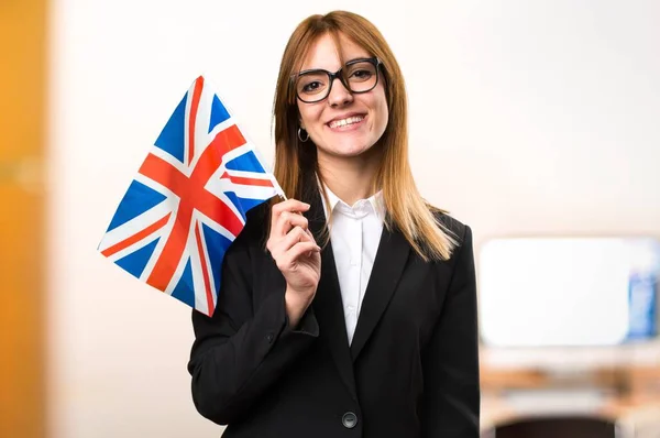 やり場のない背景にオフィスでイギリスの旗を保持している若いビジネス女性 — ストック写真