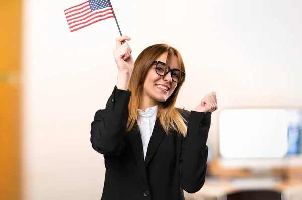 Young business woman holding an american flag in the office on unfocused background — Stock Photo, Image