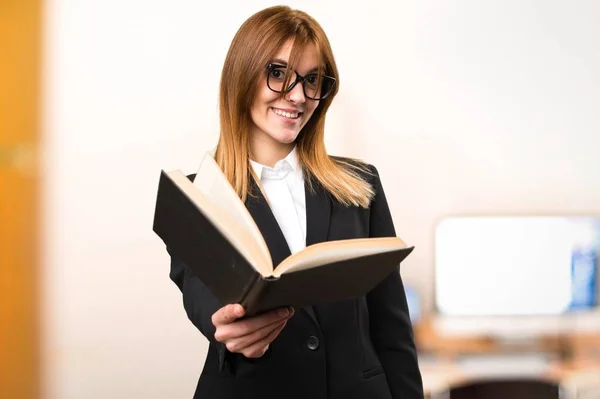 Young business woman reading book in the office on unfocused background