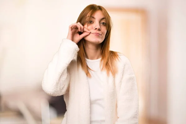 Young woman in dressing gown making silence gesture inside a room — Stock Photo, Image