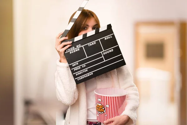 Jovem em roupão segurando uma clapperboard dentro de uma sala — Fotografia de Stock