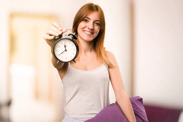 Hermosa chica en pijama sosteniendo reloj vintage dentro de una habitación —  Fotos de Stock