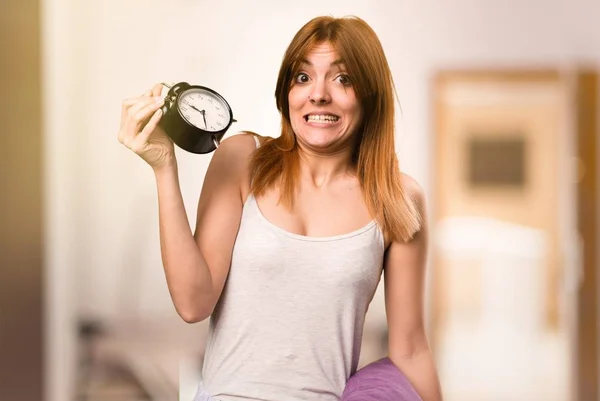 Beautiful girl in pajamas holding vintage clock inside a room — Stock Photo, Image