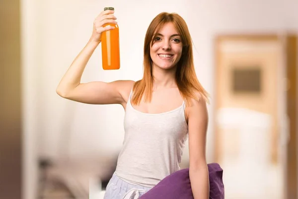 Menina bonita em pijama segurando um suco de laranja dentro de uma sala — Fotografia de Stock