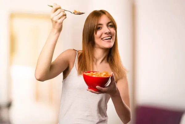 Menina bonita em pijama comendo cereais de uma tigela dentro de uma sala — Fotografia de Stock