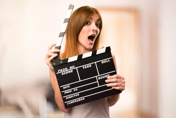 Beautiful girl in pajamas holding a clapperboard inside a room — Stock Photo, Image