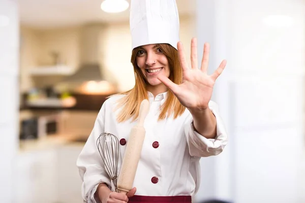 Beautiful chef woman counting five in the kitchen