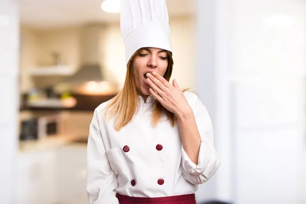 Beautiful chef woman yawning in the kitchen