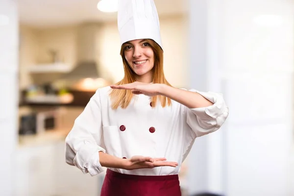 Bella chef donna che tiene qualcosa in cucina — Foto Stock