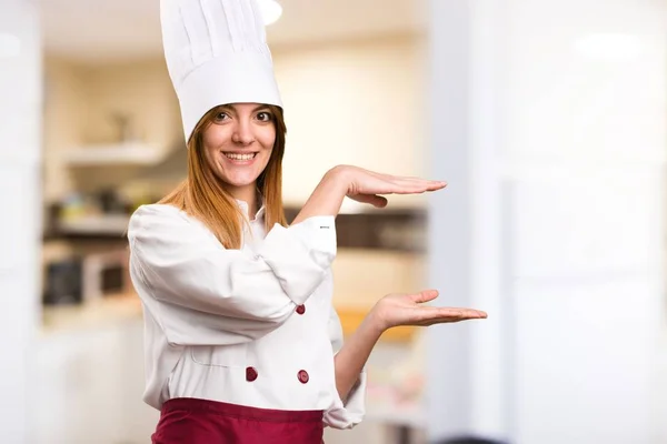 Bella chef donna che tiene qualcosa in cucina — Foto Stock