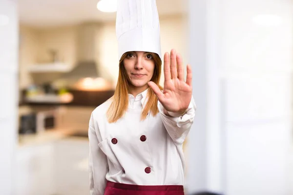 Beautiful chef woman making stop sign in the kitchen