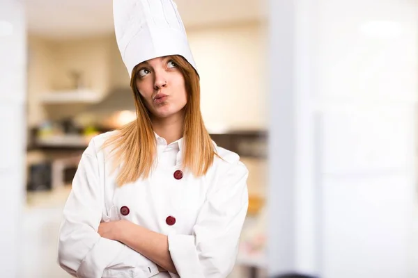 Beautiful chef woman thinking in the kitchen