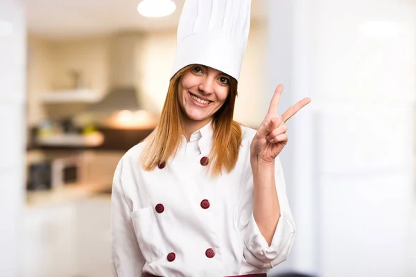 Όμορφη σεφ κάνοντας χειρονομία νίκη γυναίκα στην κουζίνα — Φωτογραφία Αρχείου