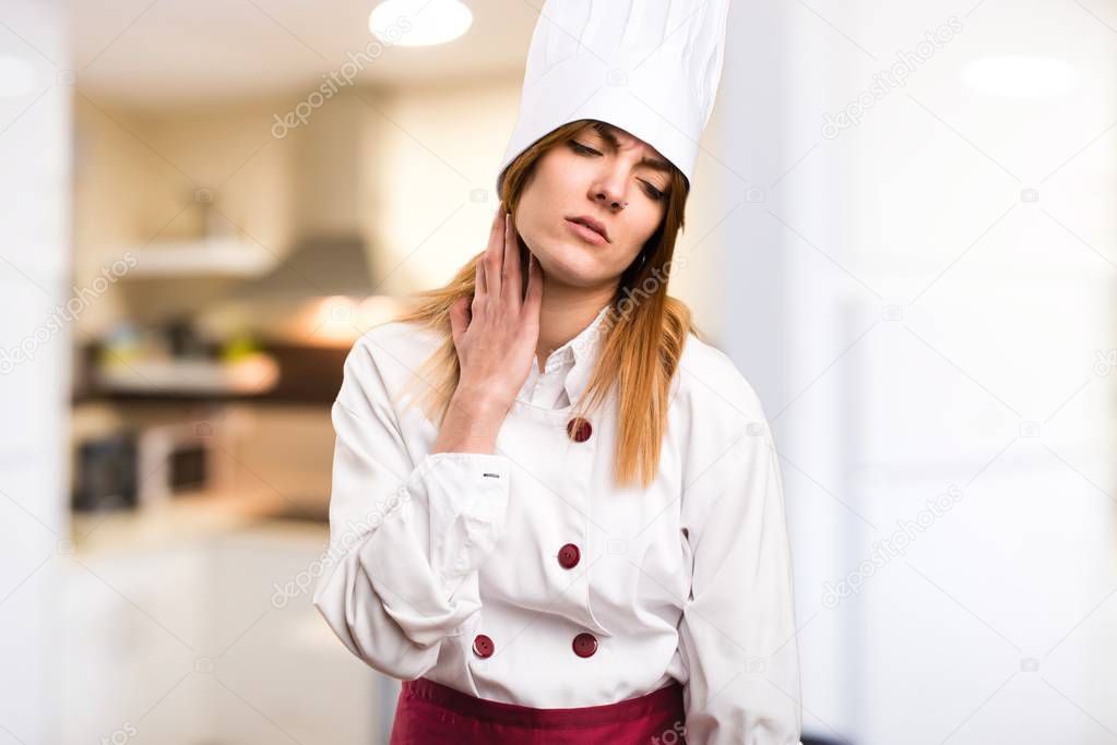 Beautiful chef woman with neck pain in the kitchen