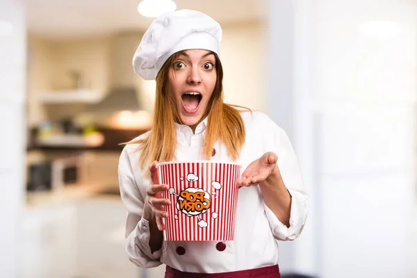 Surprised Beautiful chef woman eating popcorns in the kitchen