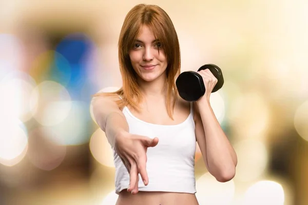 Bella donna sportiva con manubri fare un accordo su sfondo sfocato — Foto Stock