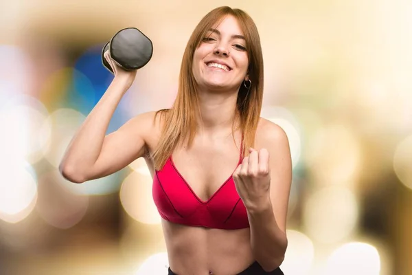 Suerte hermosa mujer del deporte con mancuernas sobre fondo desenfocado — Foto de Stock