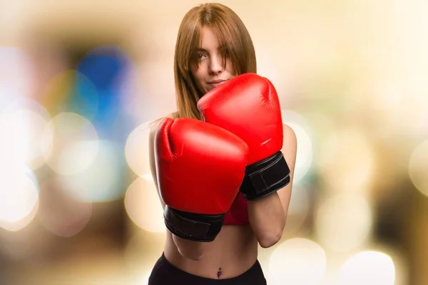 Jovem mulher esporte com luvas de boxe em fundo desfocado — Fotografia de Stock
