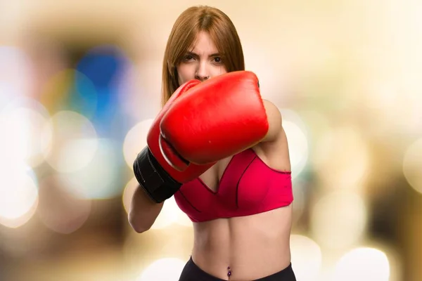 Jovem mulher esporte com luvas de boxe em fundo desfocado — Fotografia de Stock