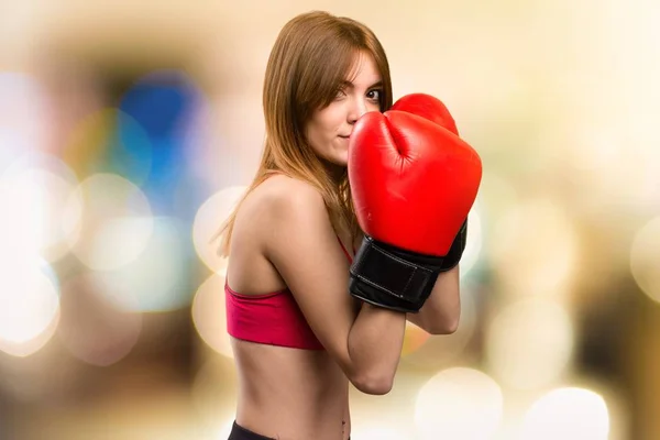 Jovem mulher esporte com luvas de boxe em fundo desfocado — Fotografia de Stock