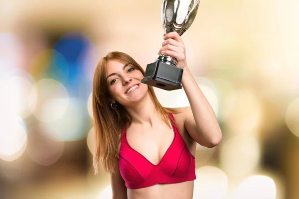 Young sport woman holding a trophy on unfocused background — Stock Photo, Image