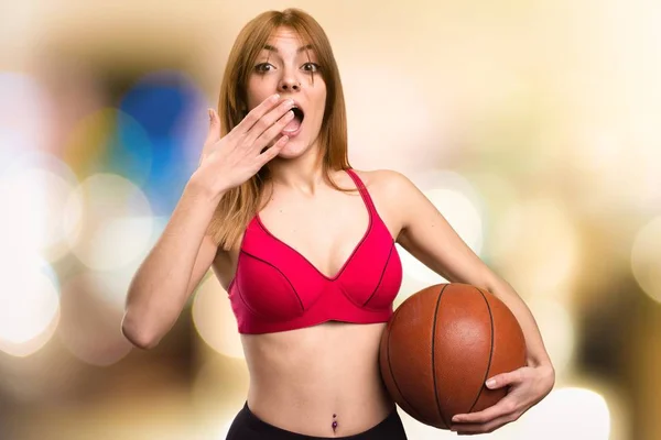 Pemuda olahraga wanita dengan bola basket pada latar belakang yang tidak fokus — Stok Foto