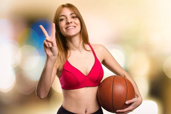 Junge Sportlerin mit Basketballball auf unkonzentriertem Hintergrund — Stockfoto
